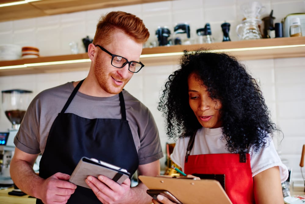 Young man and woman in red aprons making cost plan